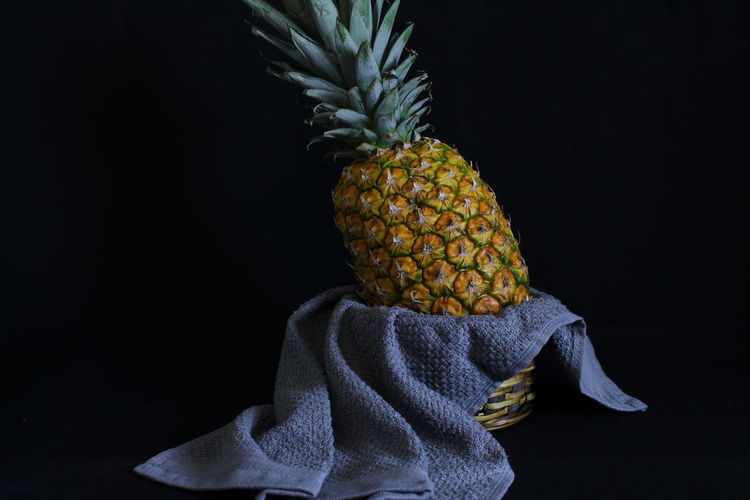 Pineapple standing in a basket and kitchen towel