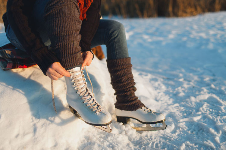 Low section of woman wearing ice skates on frozen lake