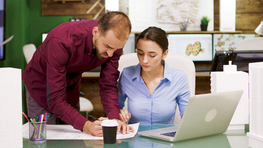 Side view of young woman using laptop at office