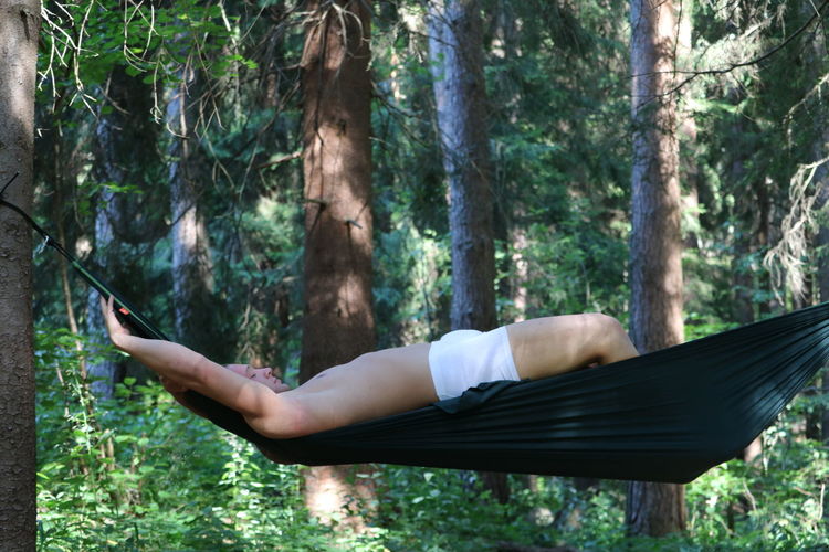 Man relaxing on tree trunk in forest