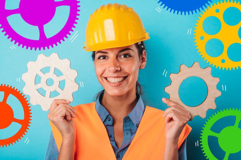 Midsection of woman holding hardhat while standing against wall