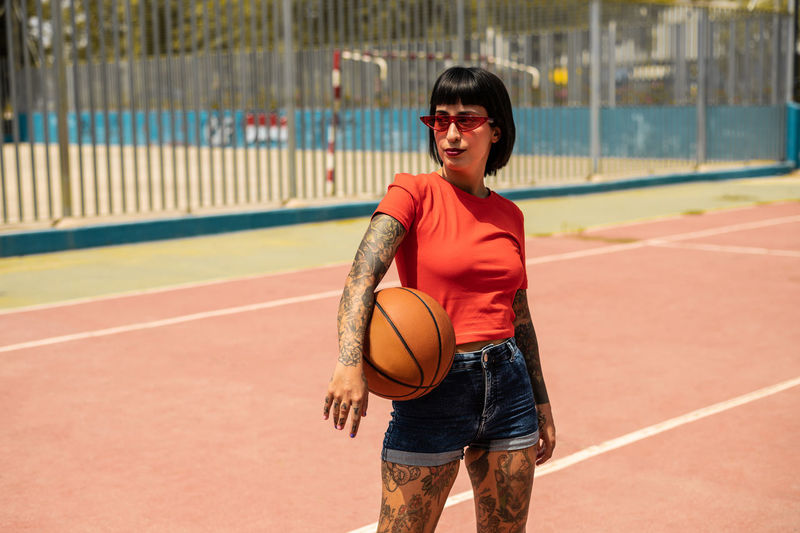 Caucasian girl with tattoos and short black hair on a sports court