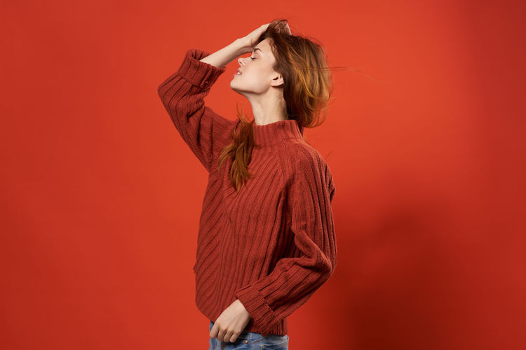 Woman standing against red background