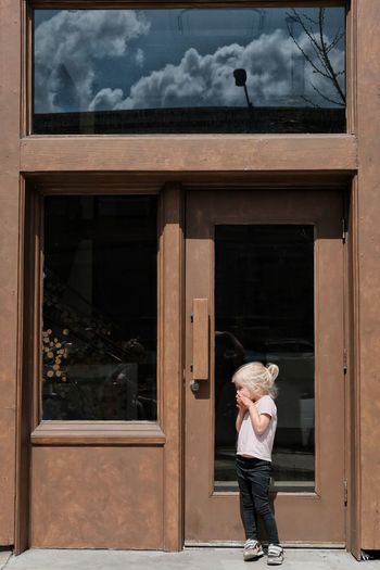 Woman standing by window of building