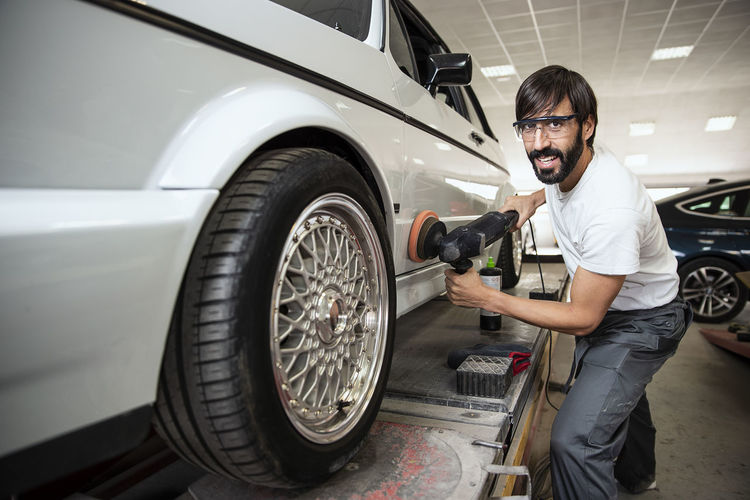 Portrait of man polishing car in factory