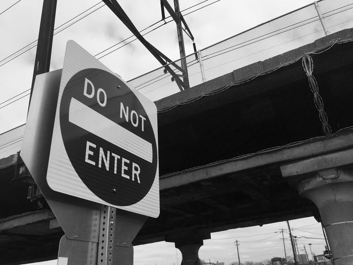 Low angle view of do not enter sign against railway bridge