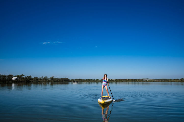 Man on boat in lake against blue sky