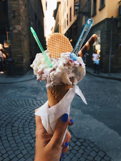 Cropped hand of woman holding ice cream cone on street