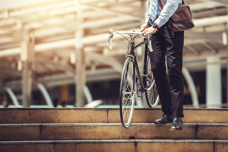 Low section of man with bicycle standing on railing