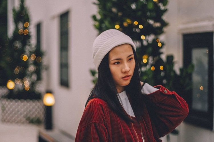 Beautiful woman against illuminated christmas trees during sunset