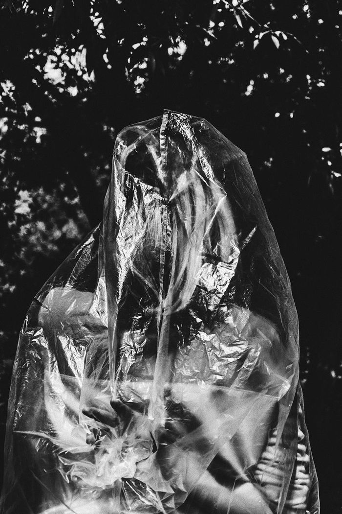 Young woman covered in plastic standing against trees