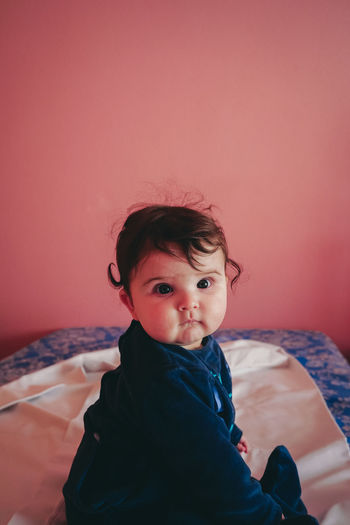 Portrait of cute girl sitting on bed at home