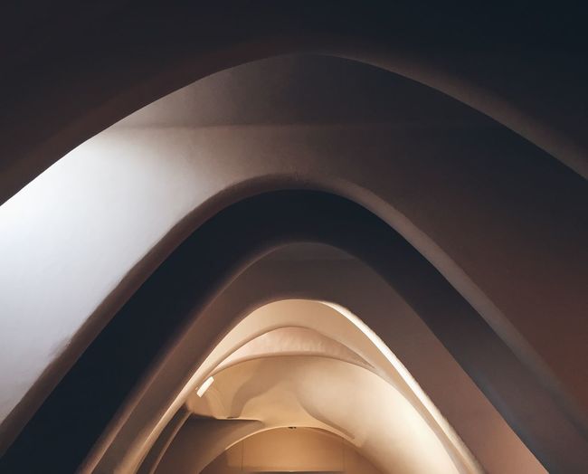 Low angle view of illuminated curve shape ceiling in building