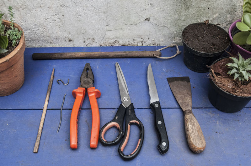 High angle view of gardening equipment amidst potted plants