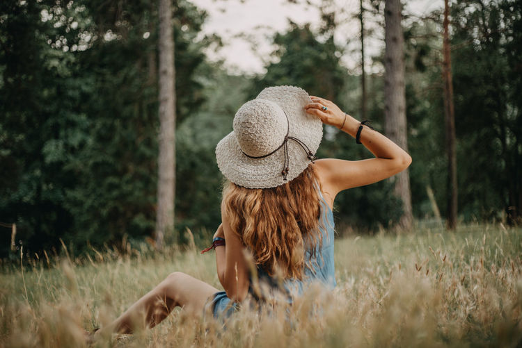 Rear view of woman wearing hat sitting on grass
