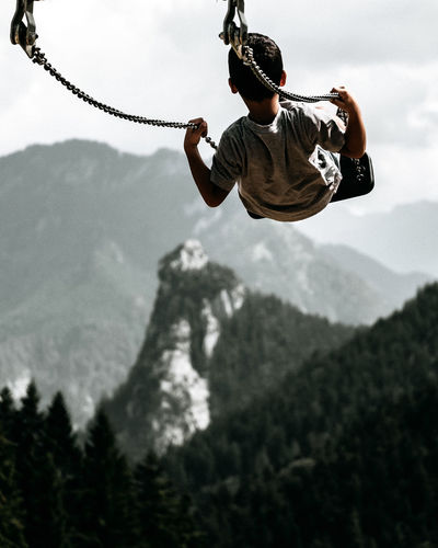 Low angle view of man jumping against mountain