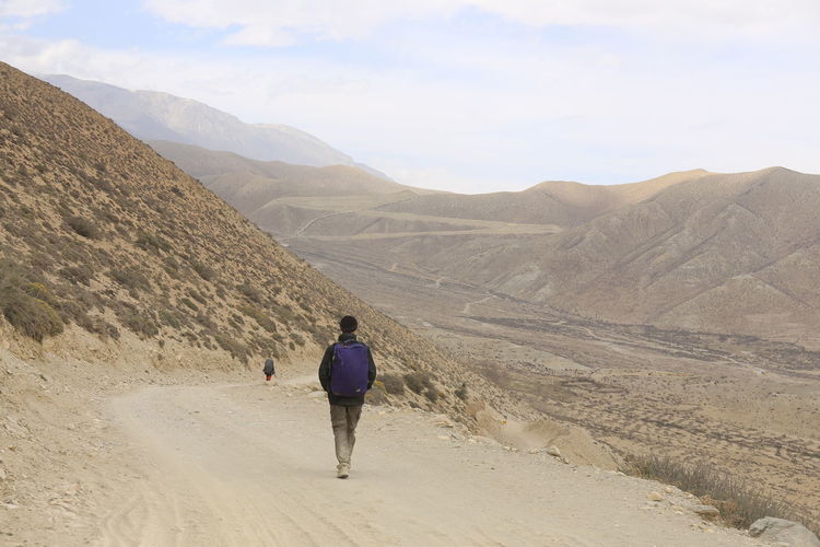 Rear view of man walking on arid landscape