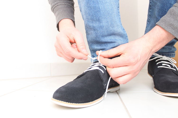 Low section of man tying shoelace on floor