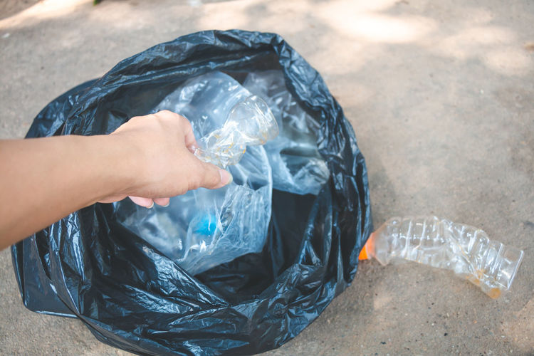 Cropped hand of woman collecting garbage in plastic bag