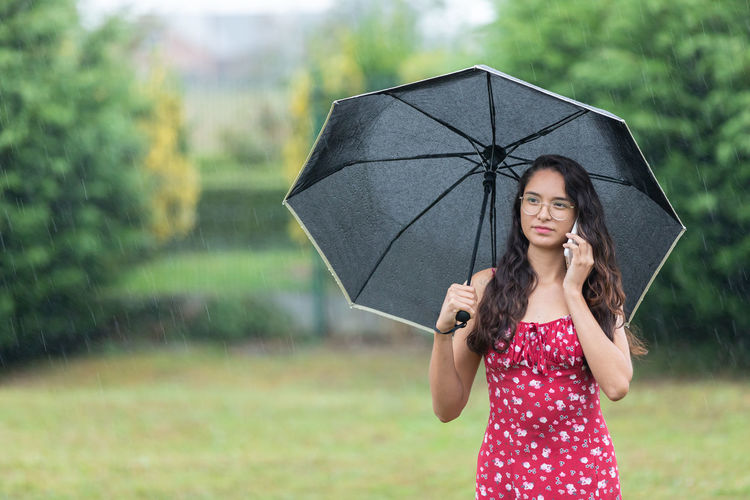 Young woman with umbrella standing outdoors