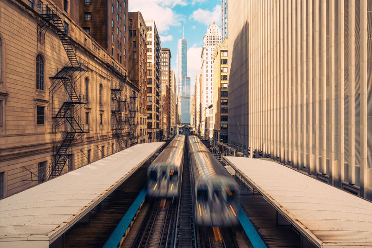 Blurred motion of trains amidst buildings in city