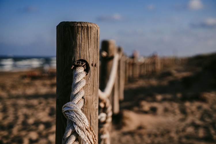 Close-up of wooden post on sand at beach against sky