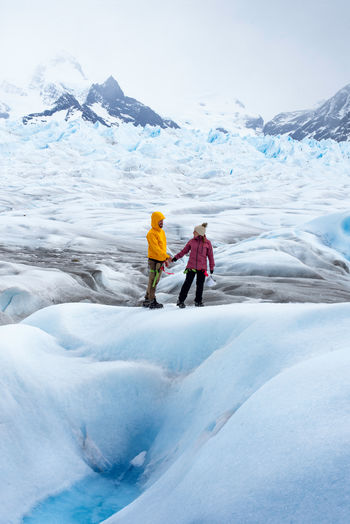 Side view of anonymous couple in outerwear admiring magnificent scenery of perito moreno glacier in mountainous region in argentina