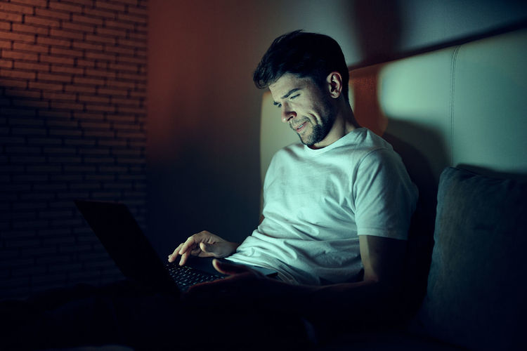 Young man using laptop while sitting on sofa at home