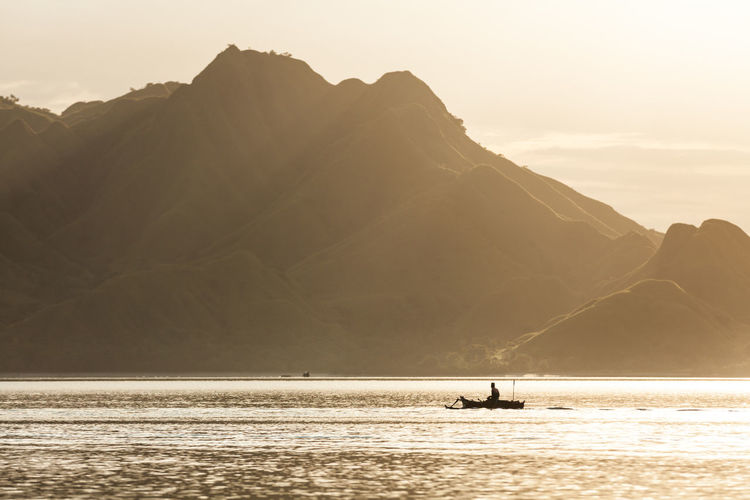 Silhouette of a boatman rowing in the golden sea