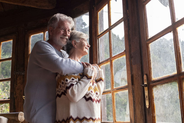 Senior couple embracing standing by window