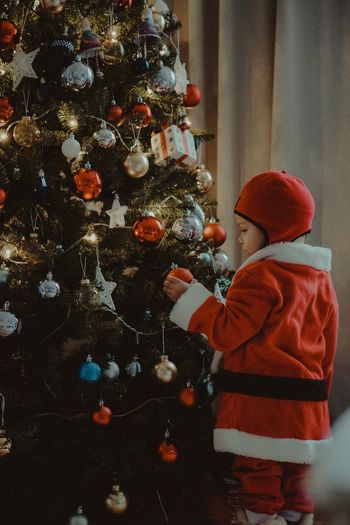 Rear view of boy standing on christmas tree