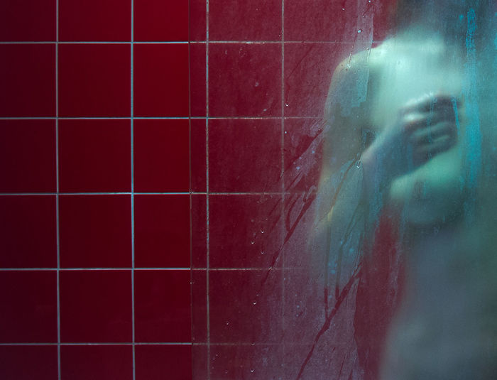 Midsection of naked woman against tiled wall