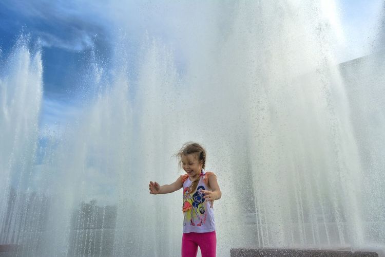 Happy girl standing against fountain 
