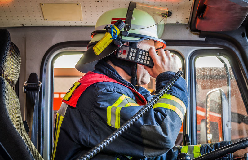 Firefighter talking on walkie-talkie while sitting fire engine