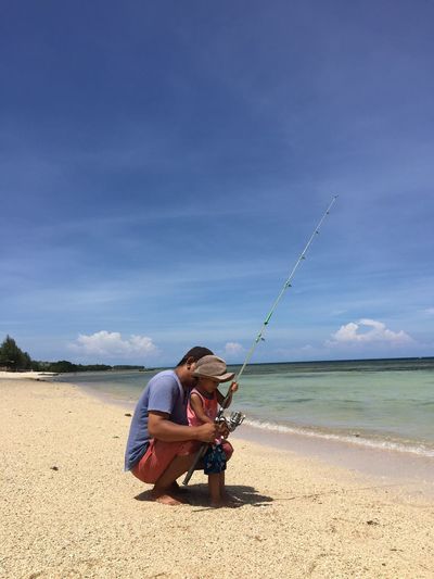 Man holding fishing net on beach against sky
