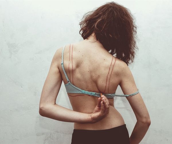 Rear view of woman standing against wall