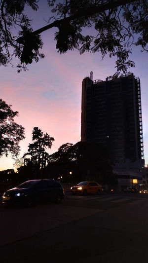 Cars on street amidst buildings in city at dusk