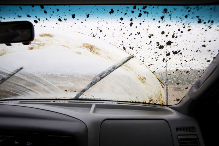 Wiper moving on dirty windshield seen through car
