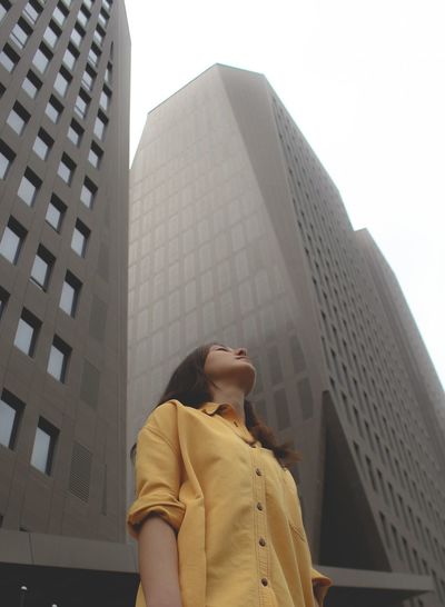 Portrait of young woman standing against modern buildings