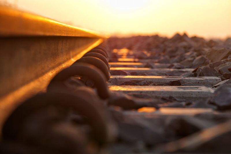 Surface level of railroad track against sky during sunset