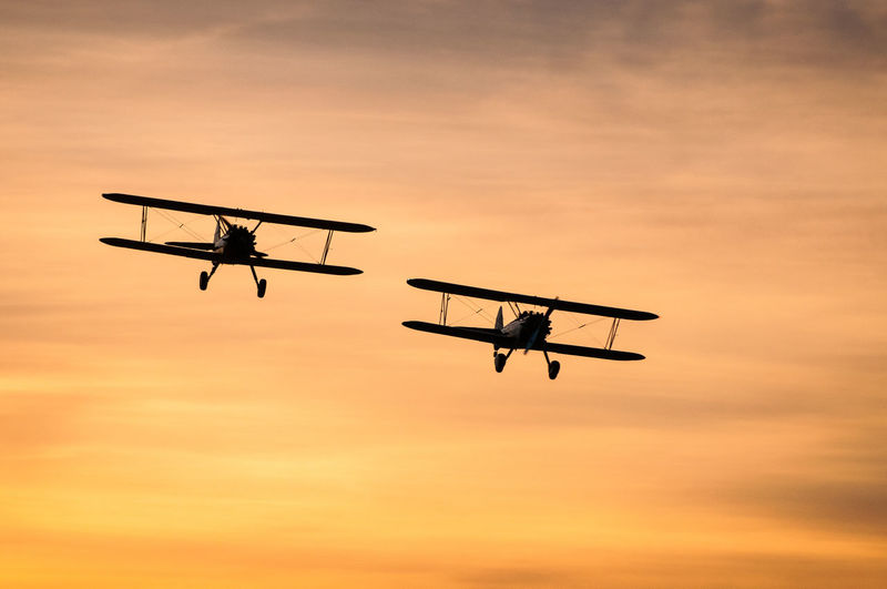 Low angle view of silhouette airplane against sky during sunset
