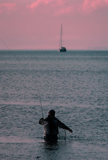 Man fishing in sea against sky