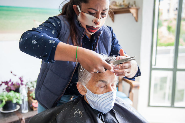 Beautician treating hair of customer at home