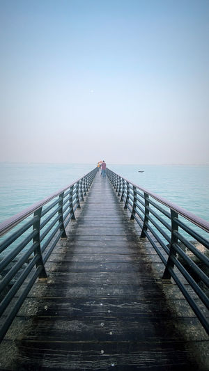 Empty pier over sea against clear sky
