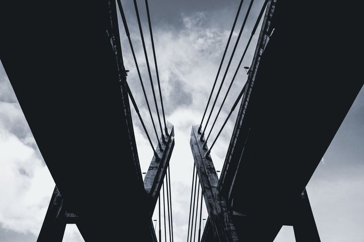 Low angle view of bridges against cloudy sky