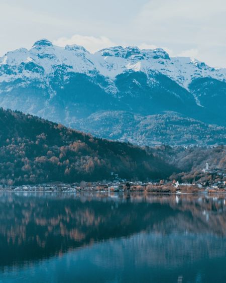 Scenic view of lake by snowcapped mountains against sky
