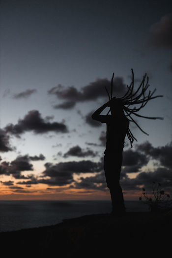 Silhouette person standing on land against sky during sunset