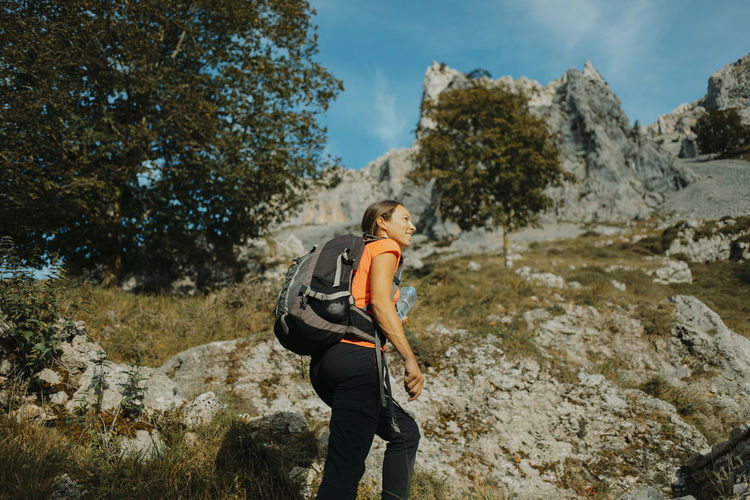 Female hiker wearing backpack hiking on cares trail at picos de europe national park, asturias, spain