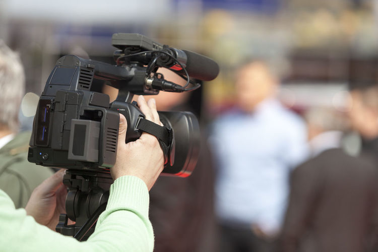 Rear view of journalist filming with television camera