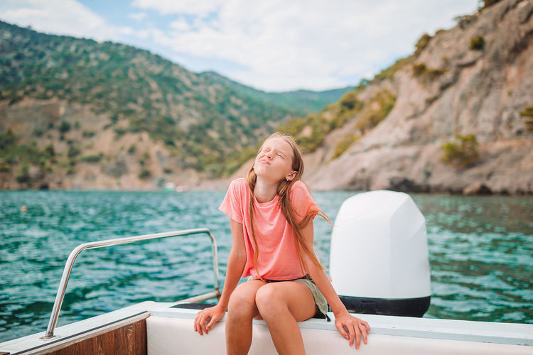 Woman sitting on boat against mountains